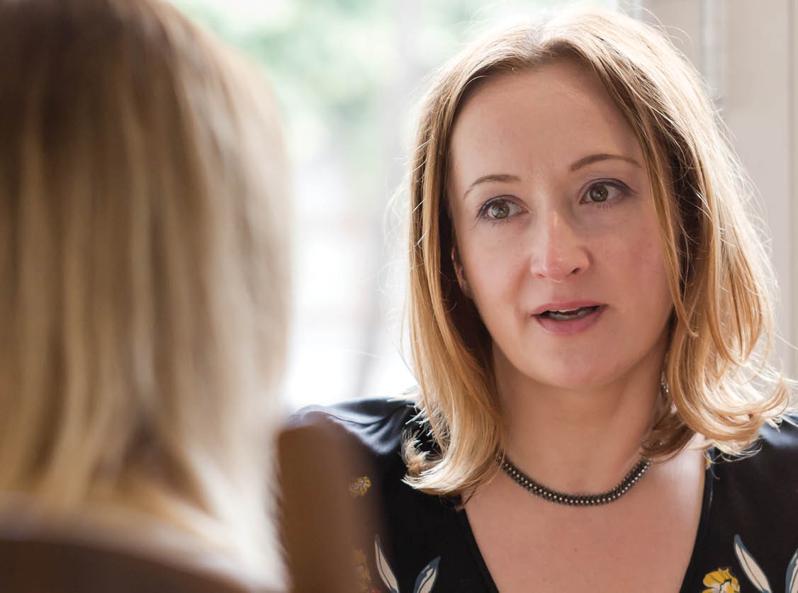 Young adult woman listen to opponent at informal business meeting. Horizontal low angle perspective, candid shot.