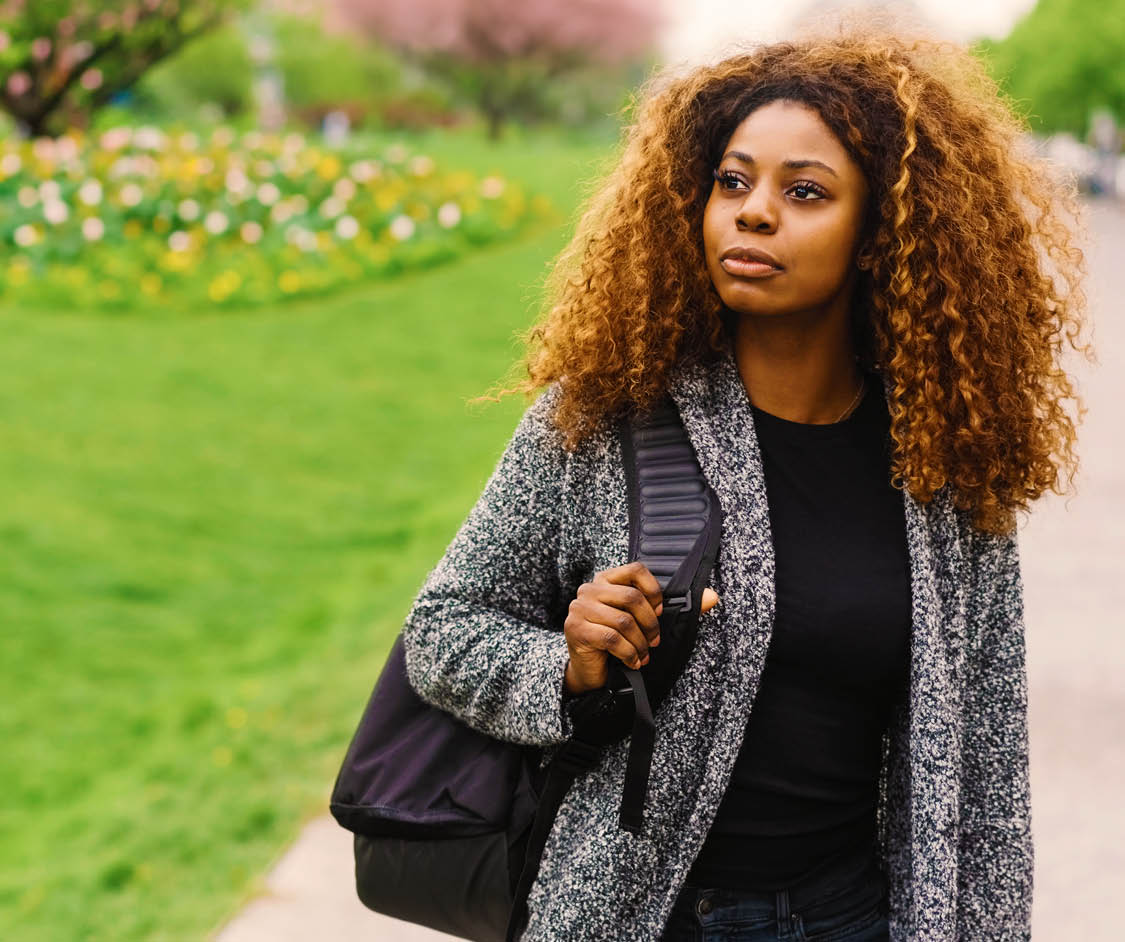 Portrait of young black woman with curly hair walking along street