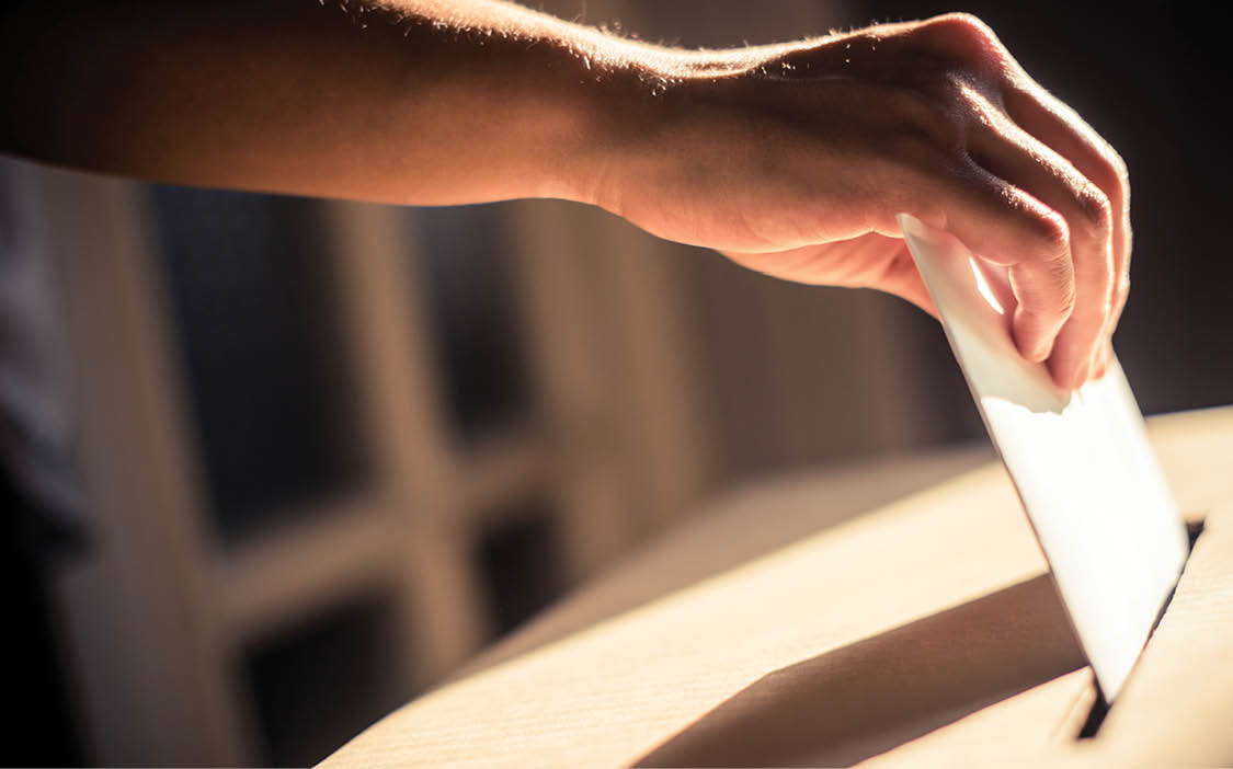 Conceptual image of a person voting, casting a ballot at a polling station, during elections.
